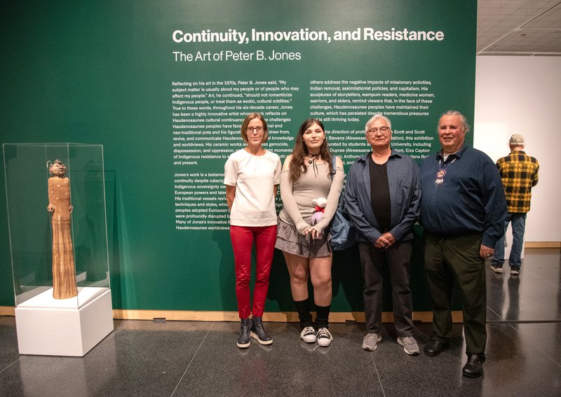 Four people standing together in front of a green wall with writing on it.