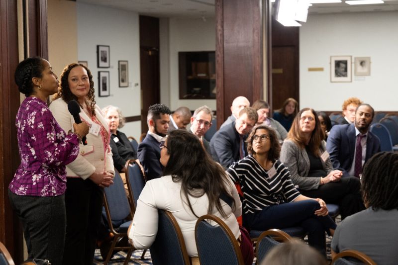 two persons standing in front of an audience fielding questions