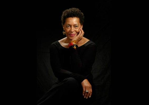 person looking at camera in black outfit with black background