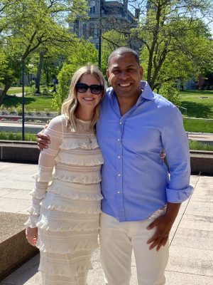 A man and a woman smile while posing for a photo outside.