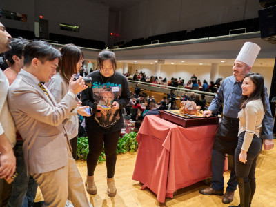 Students gather around chef carving turkey