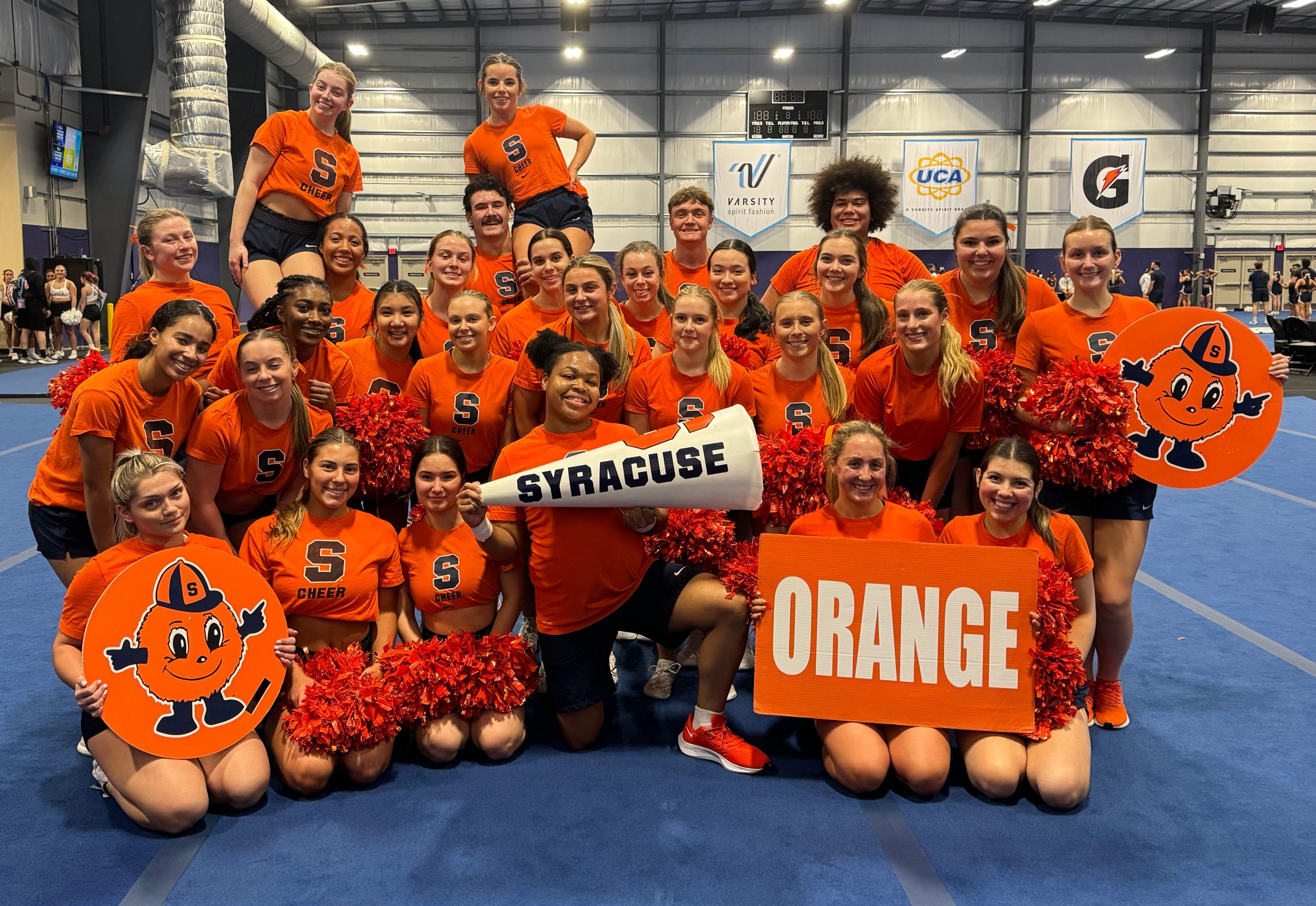 Group of Syracuse Cheerleaders all huddled together posing for a picture.