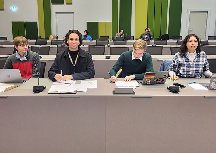 four people sitting at table in conference room