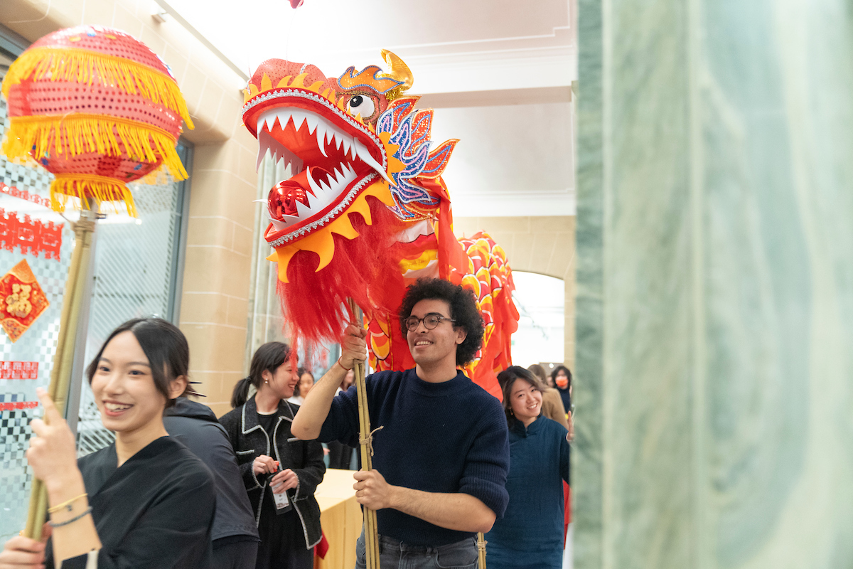 Students wearing black carrying a dragon. 