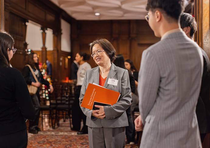 three people talking with others in the background