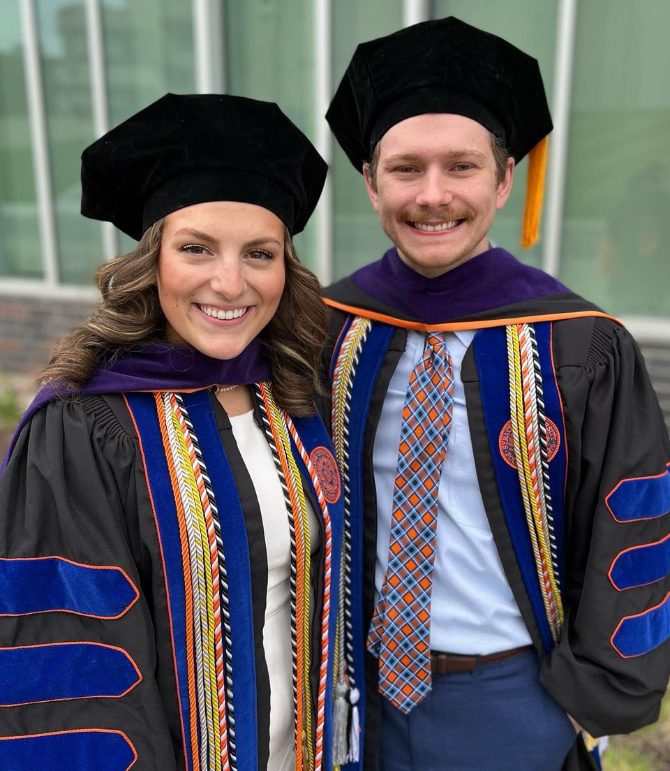 Two people in graduation cap and gown standing together for a photo.