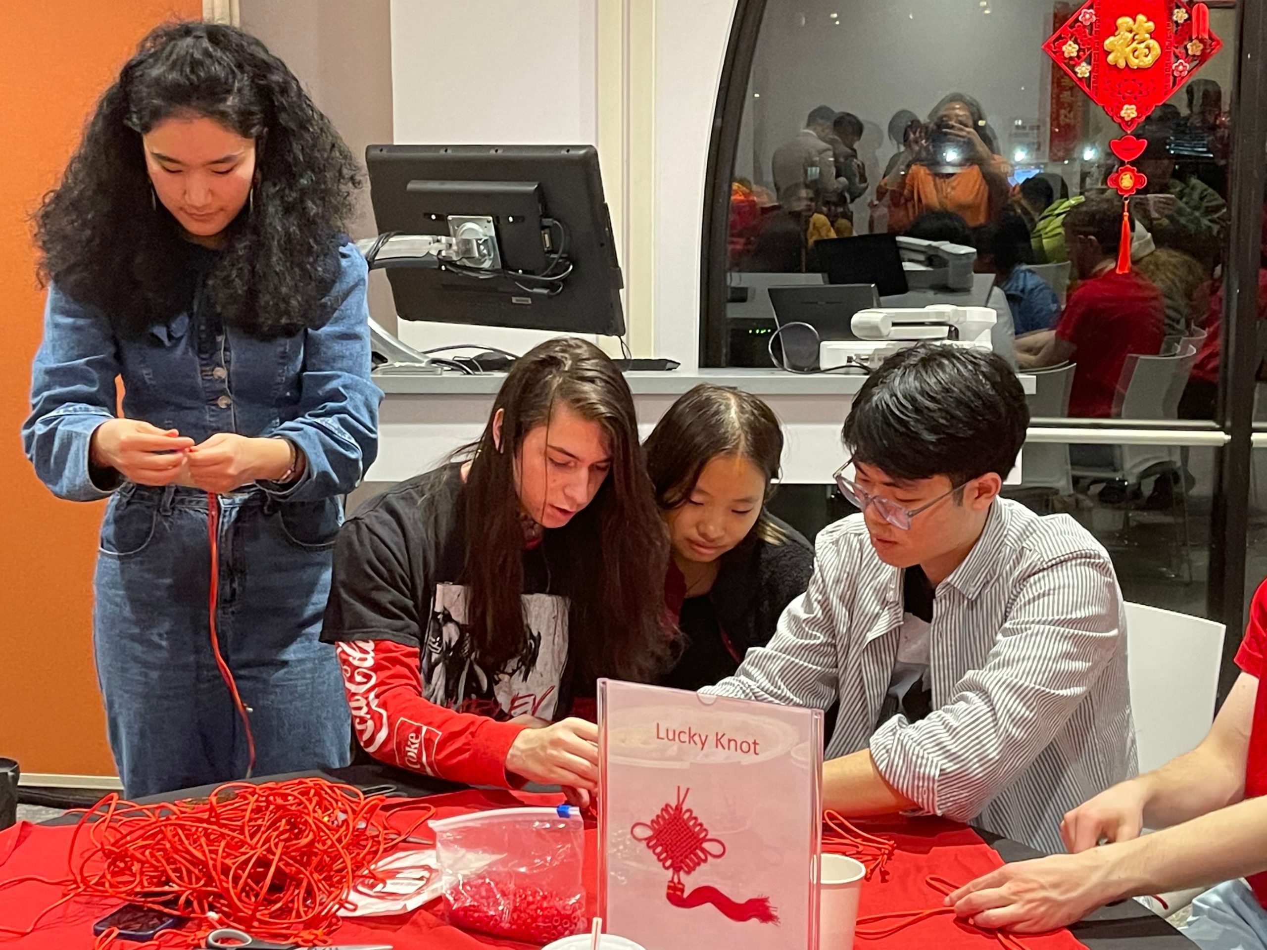 Three people sitting at a table and one standing new by working on an activity