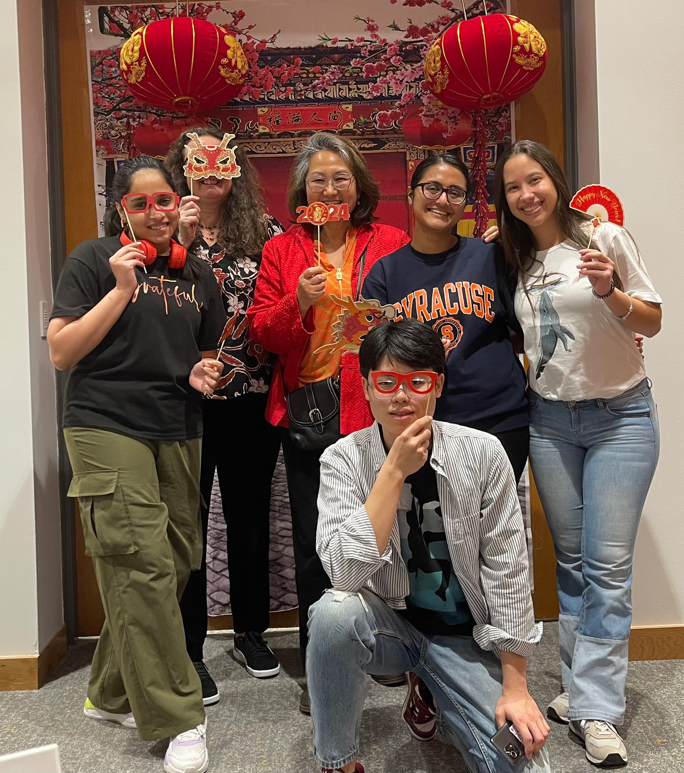 Six people posing together for a photo with photo booth props