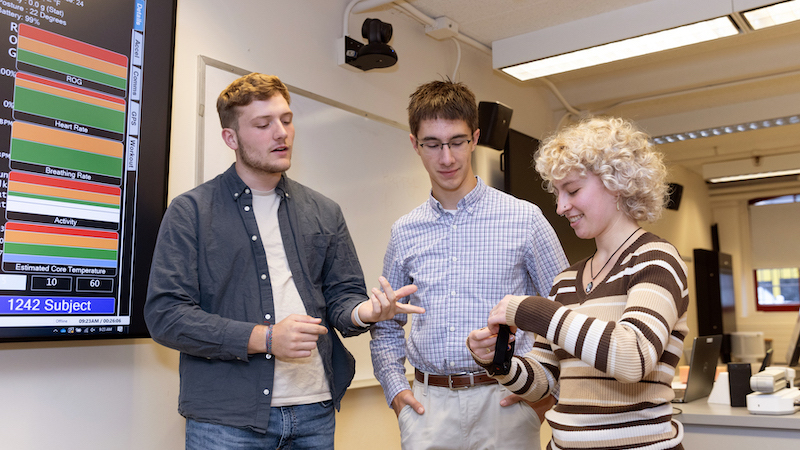 Three people standing together speaking.