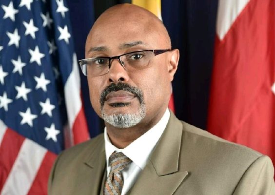 A man poses for a headshot with the American flag in the background.