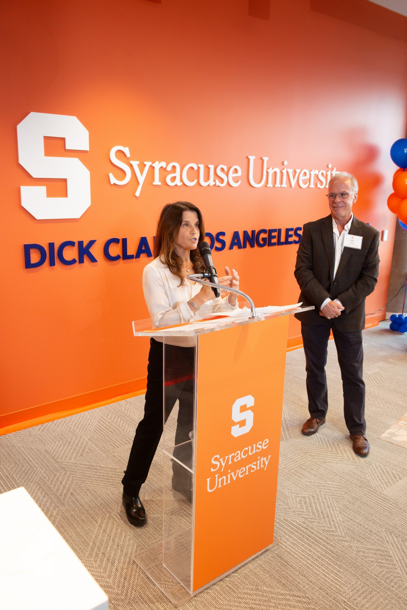 person speaking at podium with another person behind them