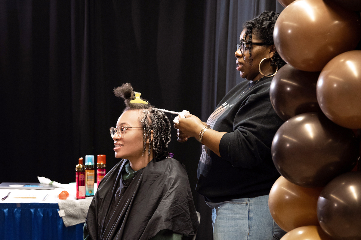 A woman works on a student's hair.