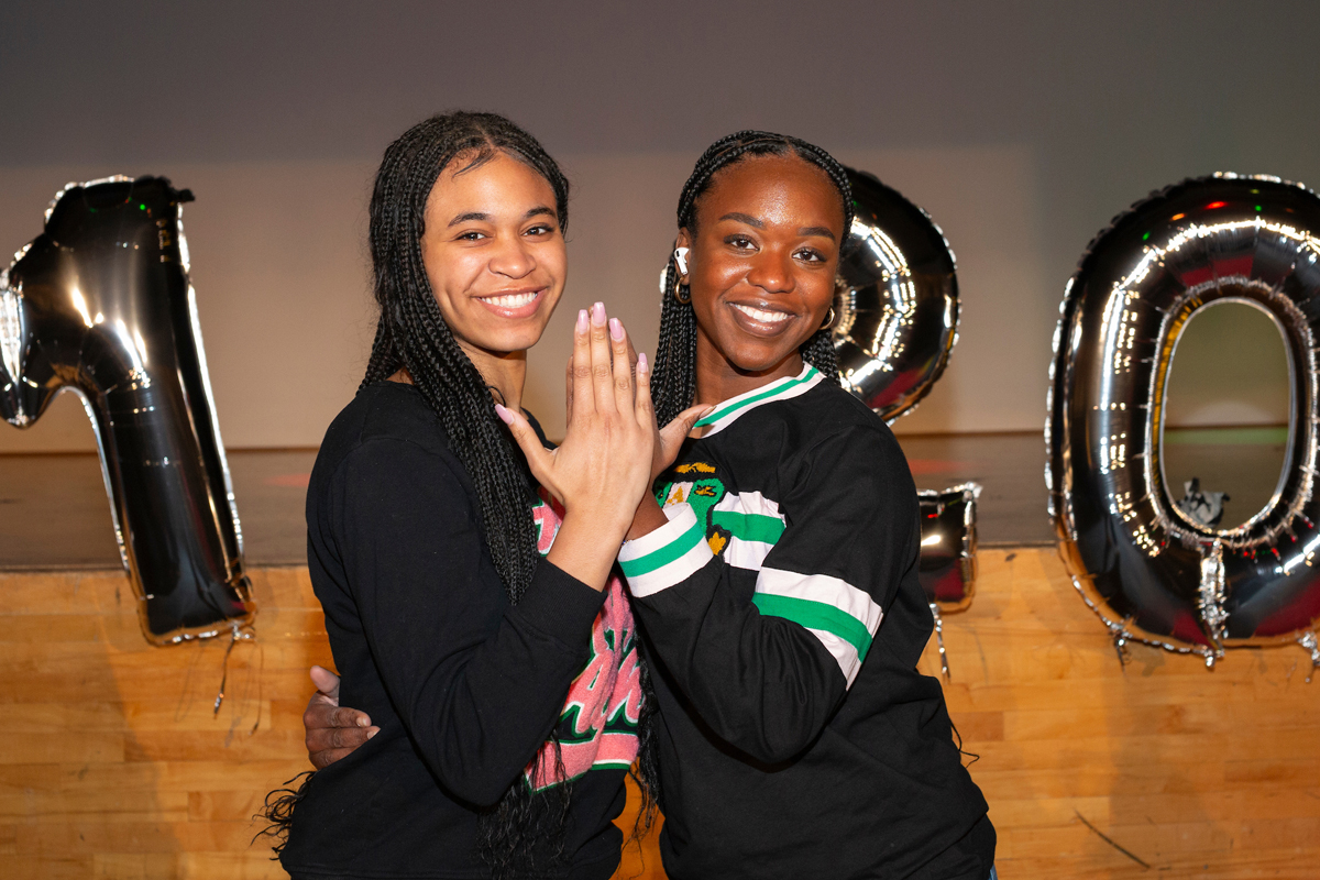 Two students smile while high fiving each other.