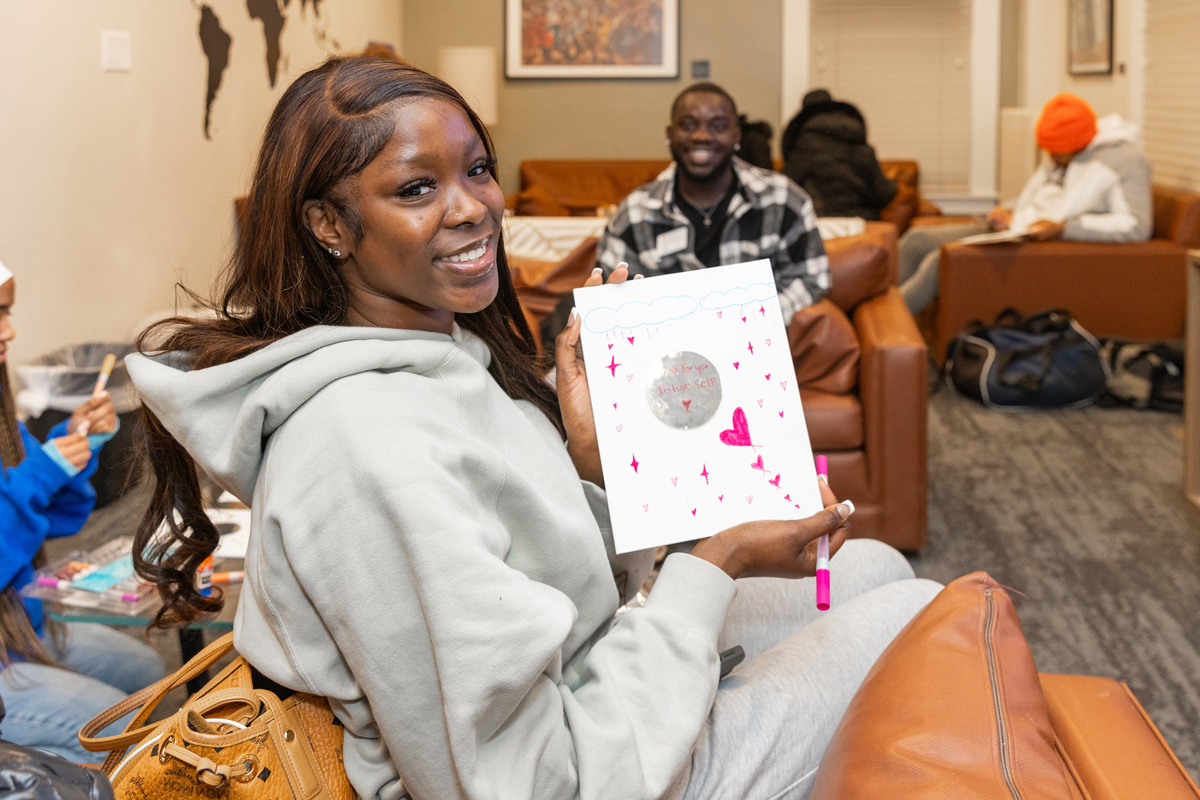 A woman poses with a journal she designed.