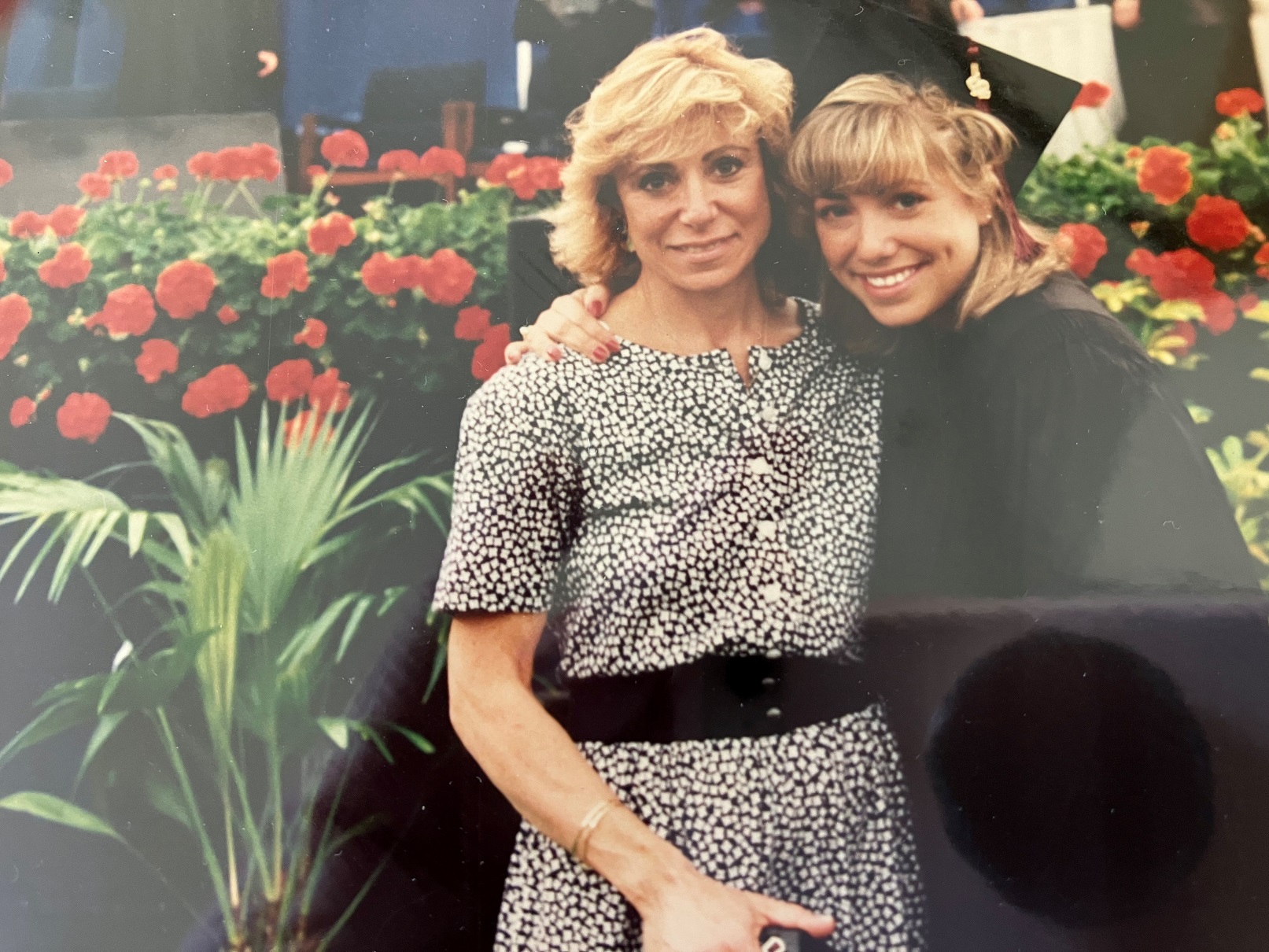 two people hugging, with one of them in a graduation cap and gown