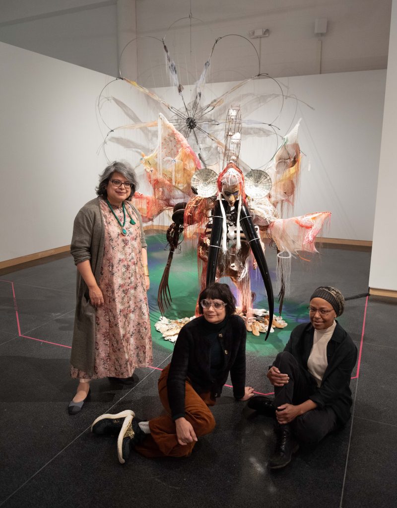 Three people gathered in front of an art display