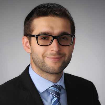 A man smiles while posing for a headshot.