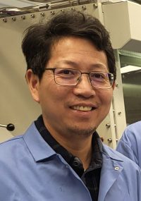 man with glasses wearing lab coat looking at camera 