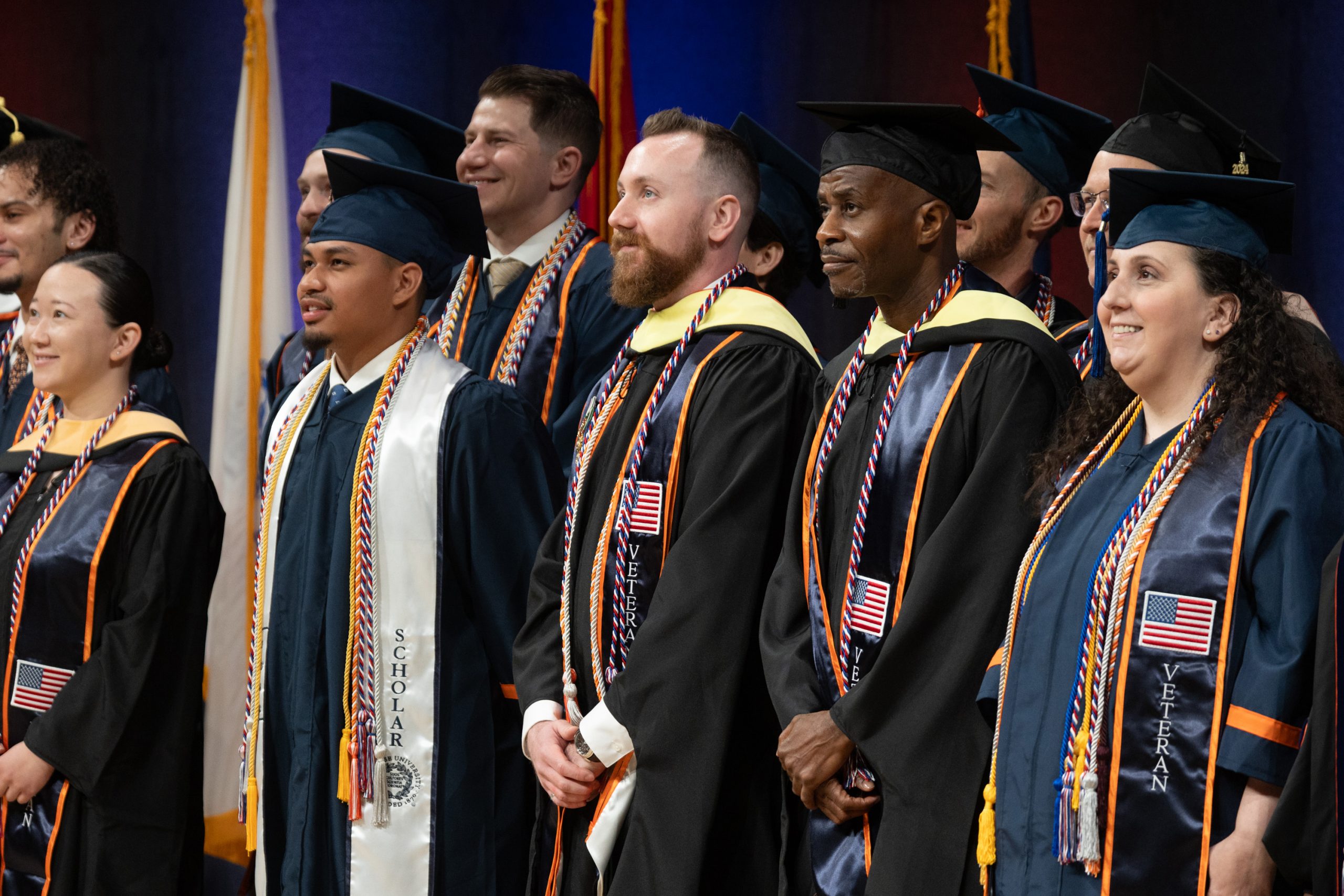 Group of people standing on a stage in cap and gowns