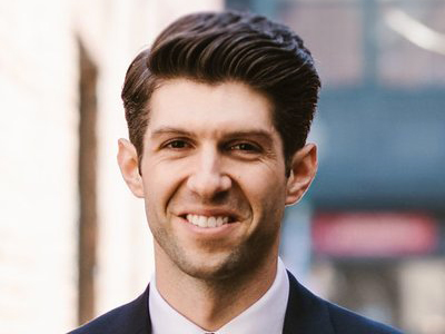 A man smiles while posing for a headshot.