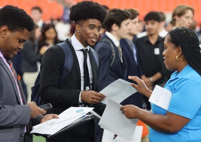 Two students meet with an employer to discuss potential job opportunities.