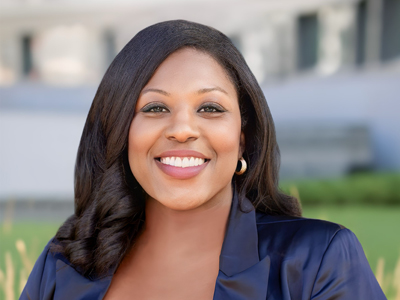 A woman smiles while posing for a headshot outdoors.