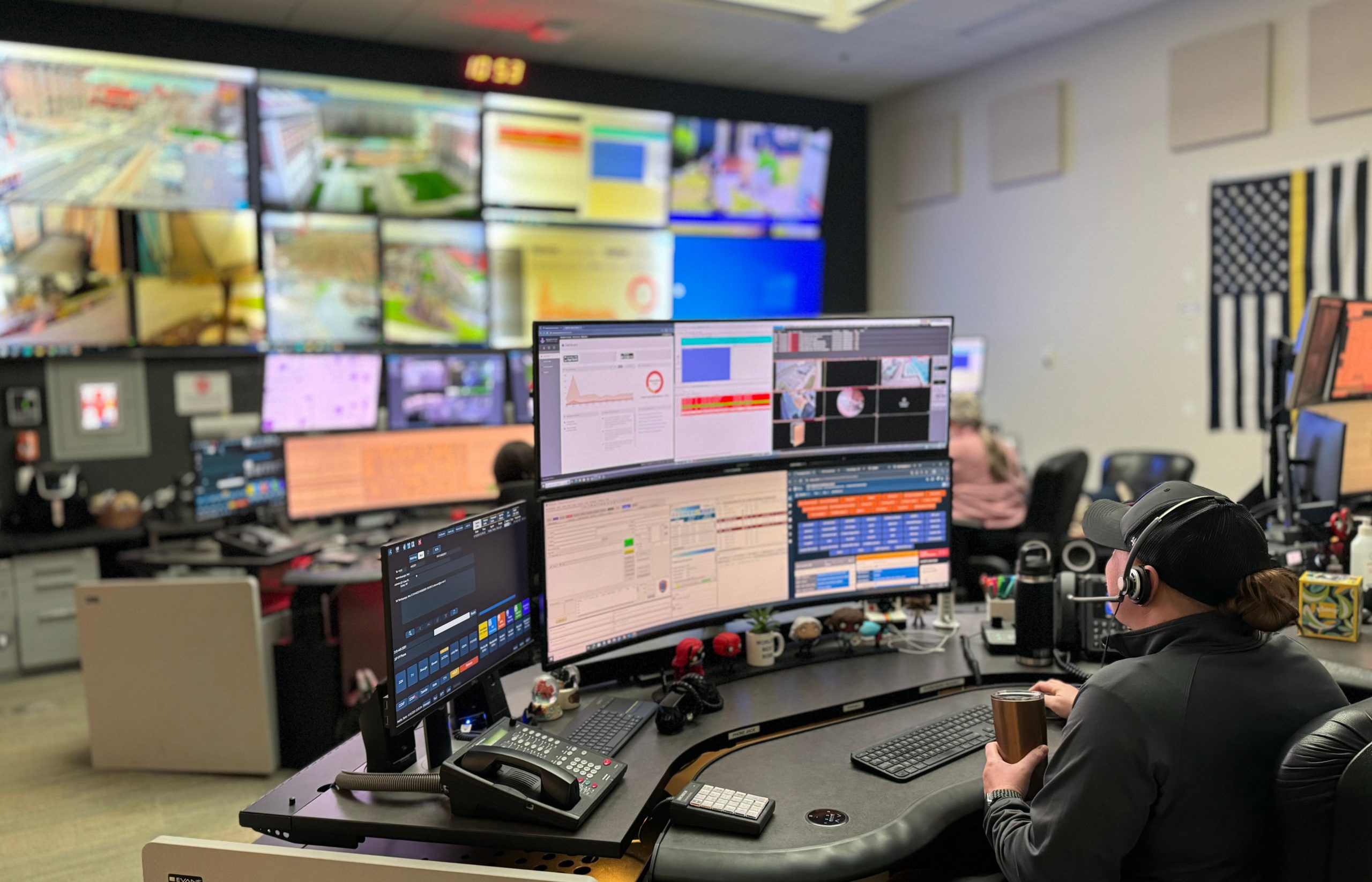 Dispatcher sitting at a desk with a bank of computer monitors.