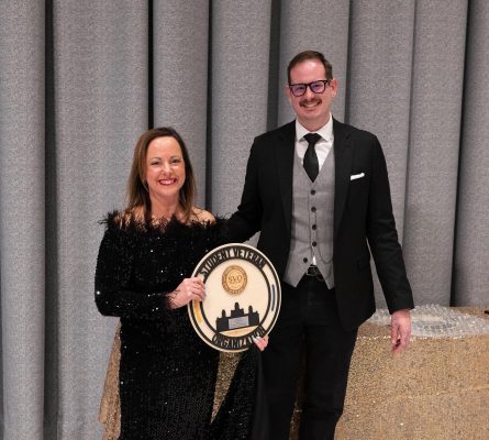 Two people standing together with one holding a round award