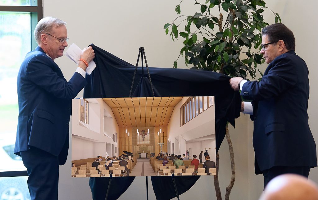 two people unveiling building artwork