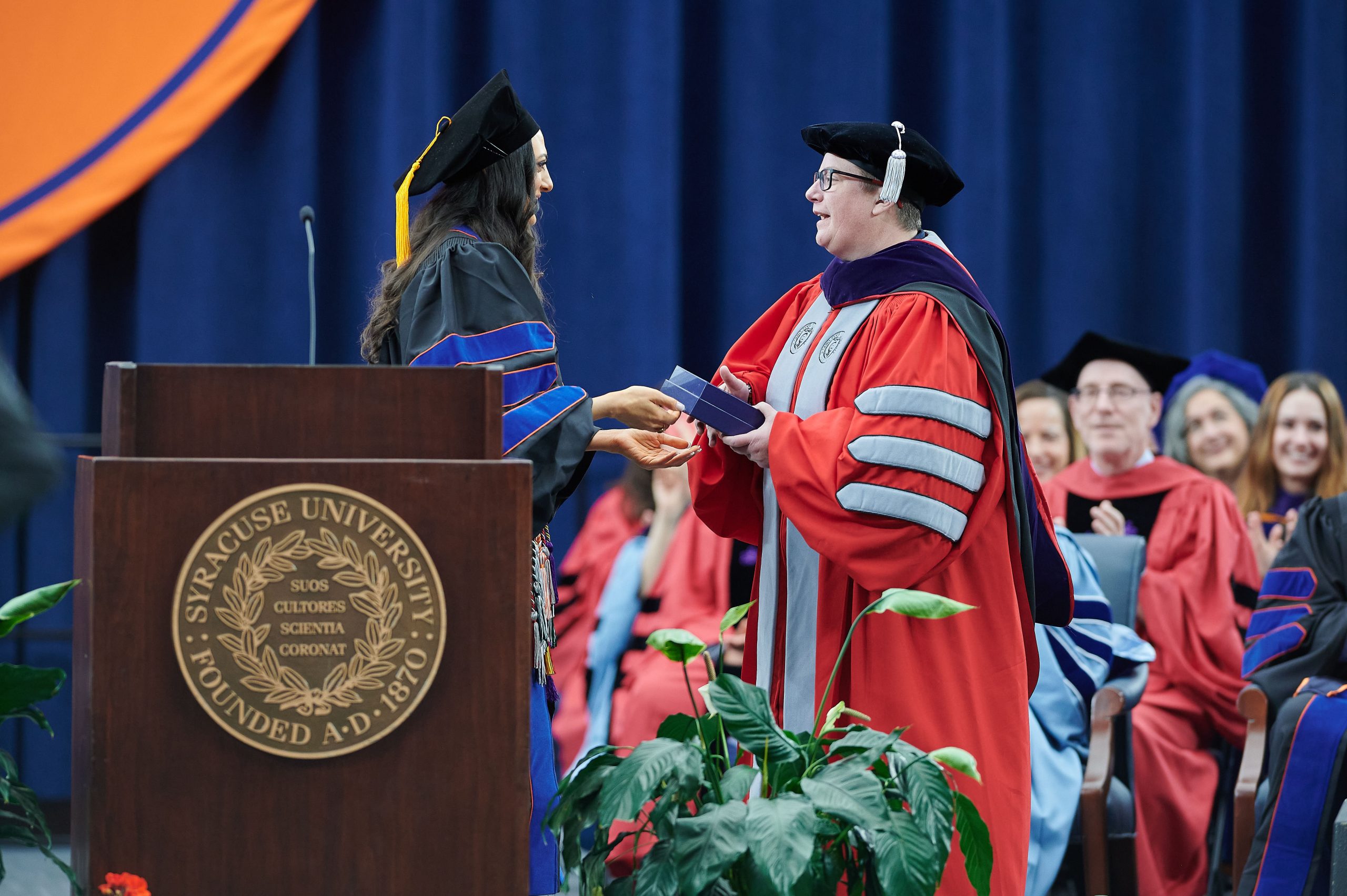 One person giving another person an award on stage at Commencement