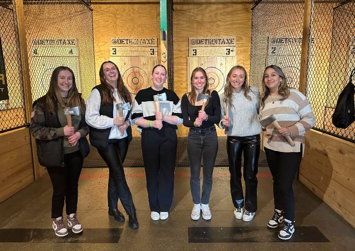 Six students standing together holding axes