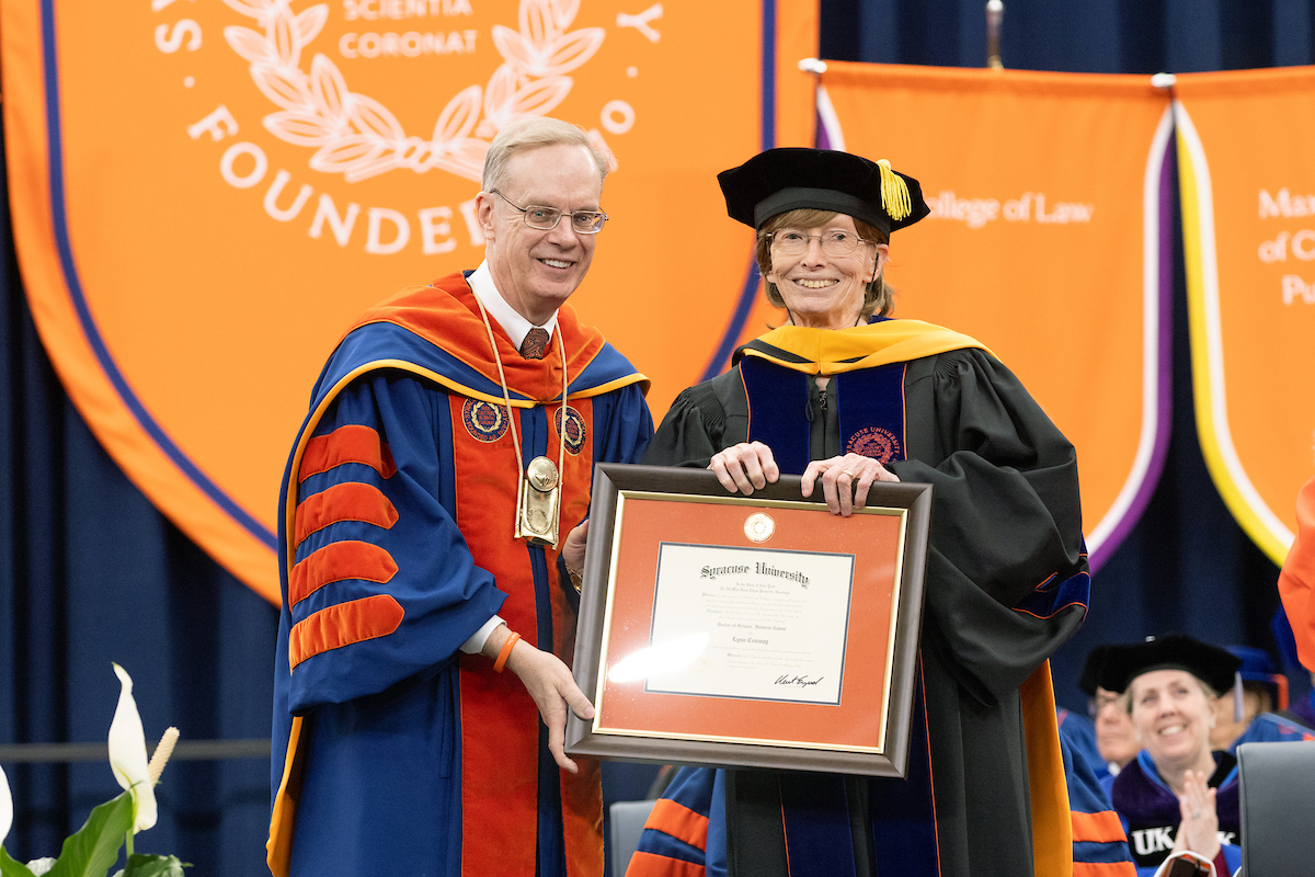 Two people standing next to one another holding a large picture frame