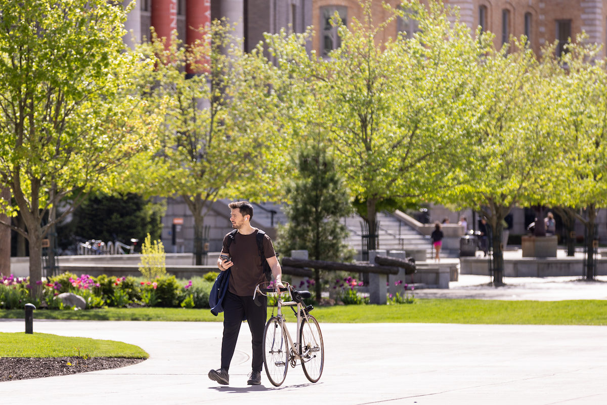 A student walks his bike in front of Carnegie Library.