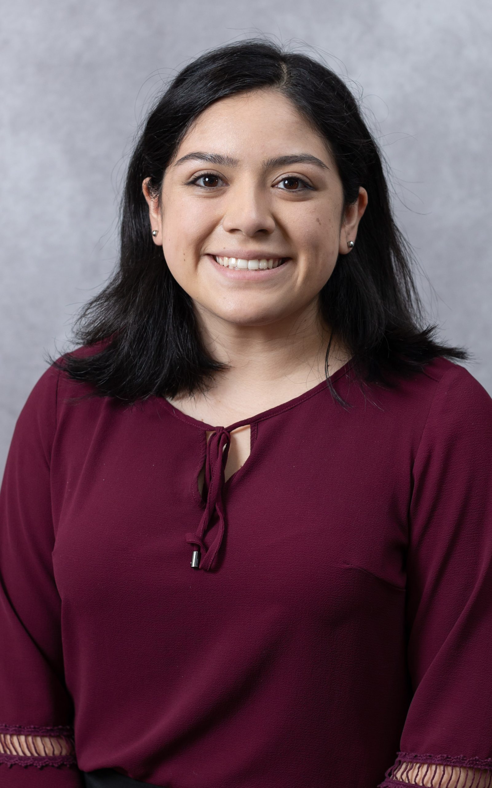 A woman smiles while posing for a headshot indoors.