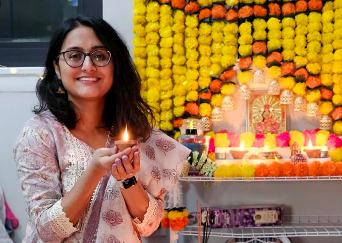 A woman smiles while posing for a photo holding a candle.