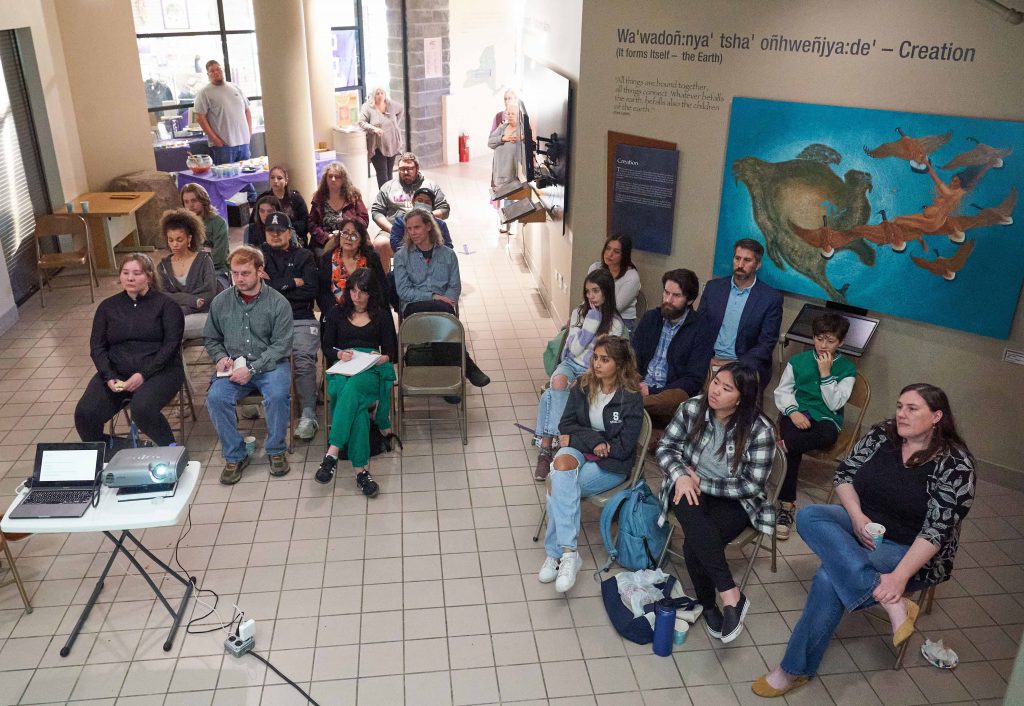 people sitting in two groups of chairs in a room for a presentation