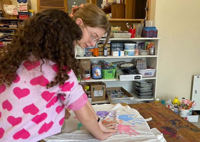 A woman uses handprints from one of her students for her hand-made dress.
