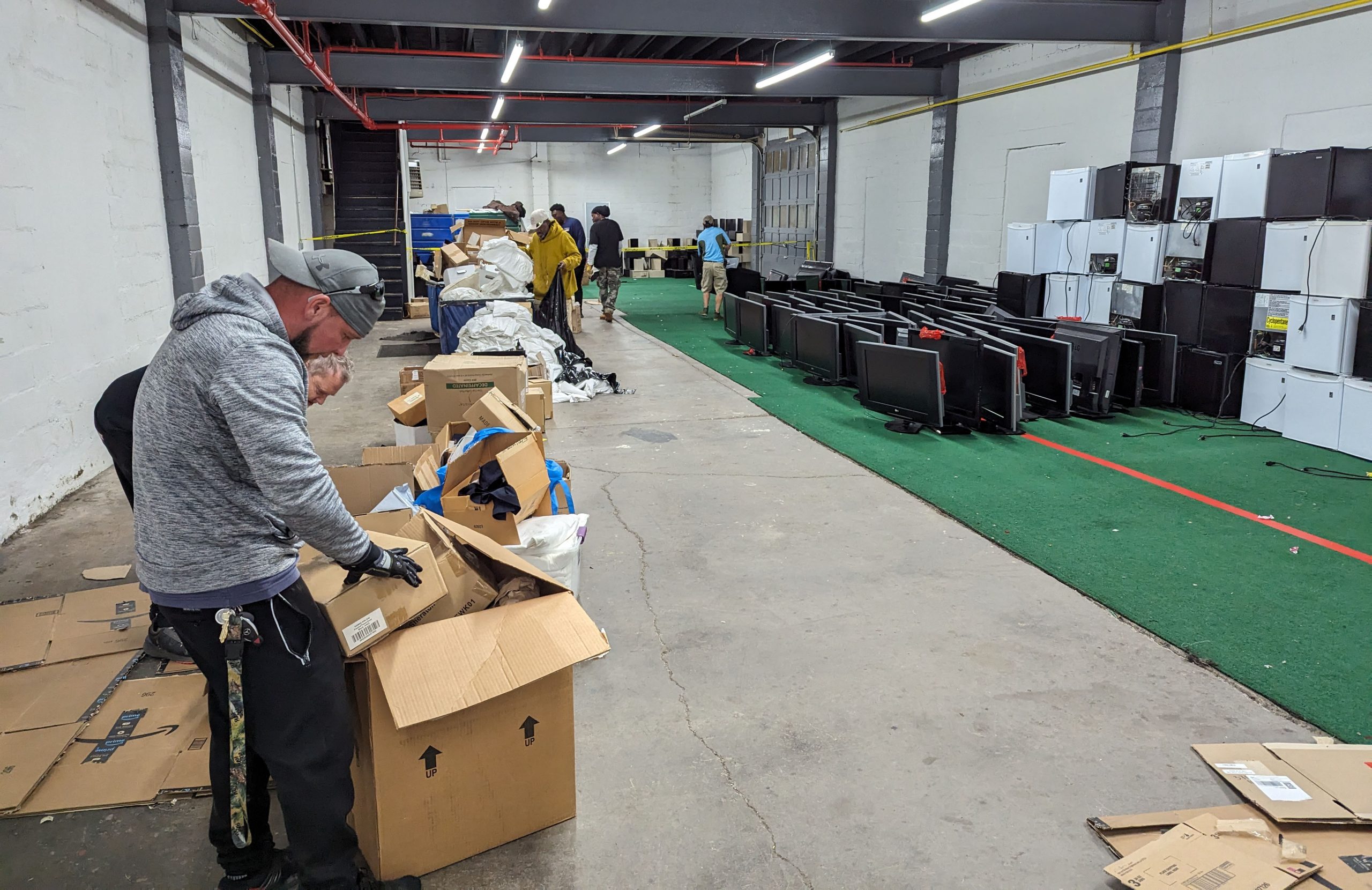 Warehouse full of tvs and mini fridges that were donated to be sorted and donated.