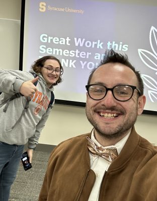 A man in a bow tie smiles for a photo with a student.