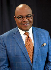 A man smiles while posing for a headshot.