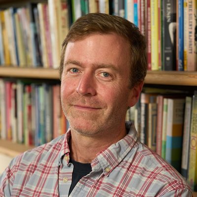 person standing up against a bookshelf