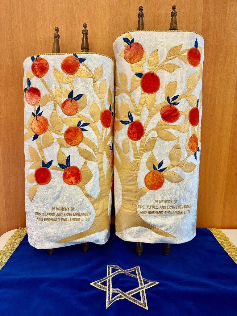 Torah scrolls with covers on them of orange trees.