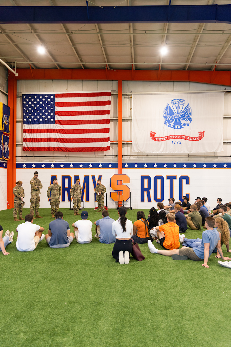 ARMY ROTC facility with students sitting on the turf ground, while people in military uniforms face them
