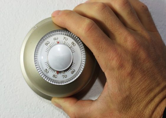 Hand turning the dial of a thermostat