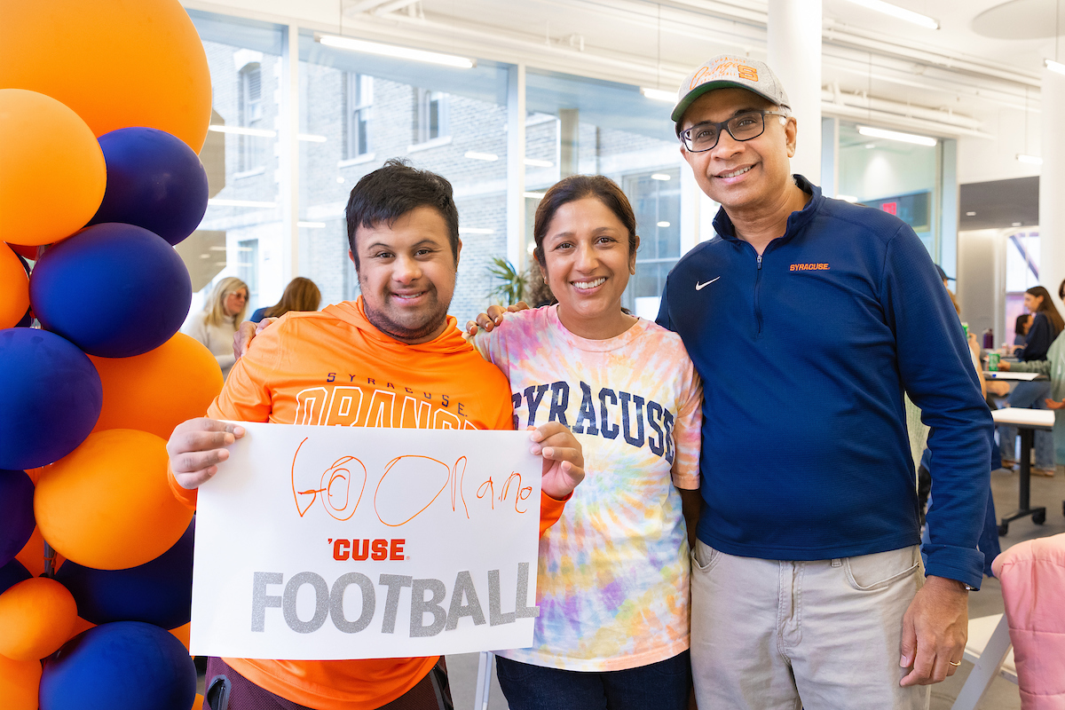 A student poses with two family members inside a residence hall on campus.
