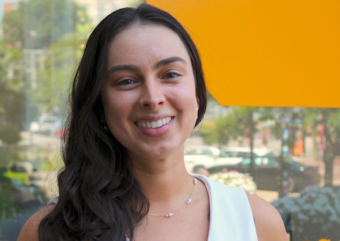 A woman smiles while posing for a photo outdoors.