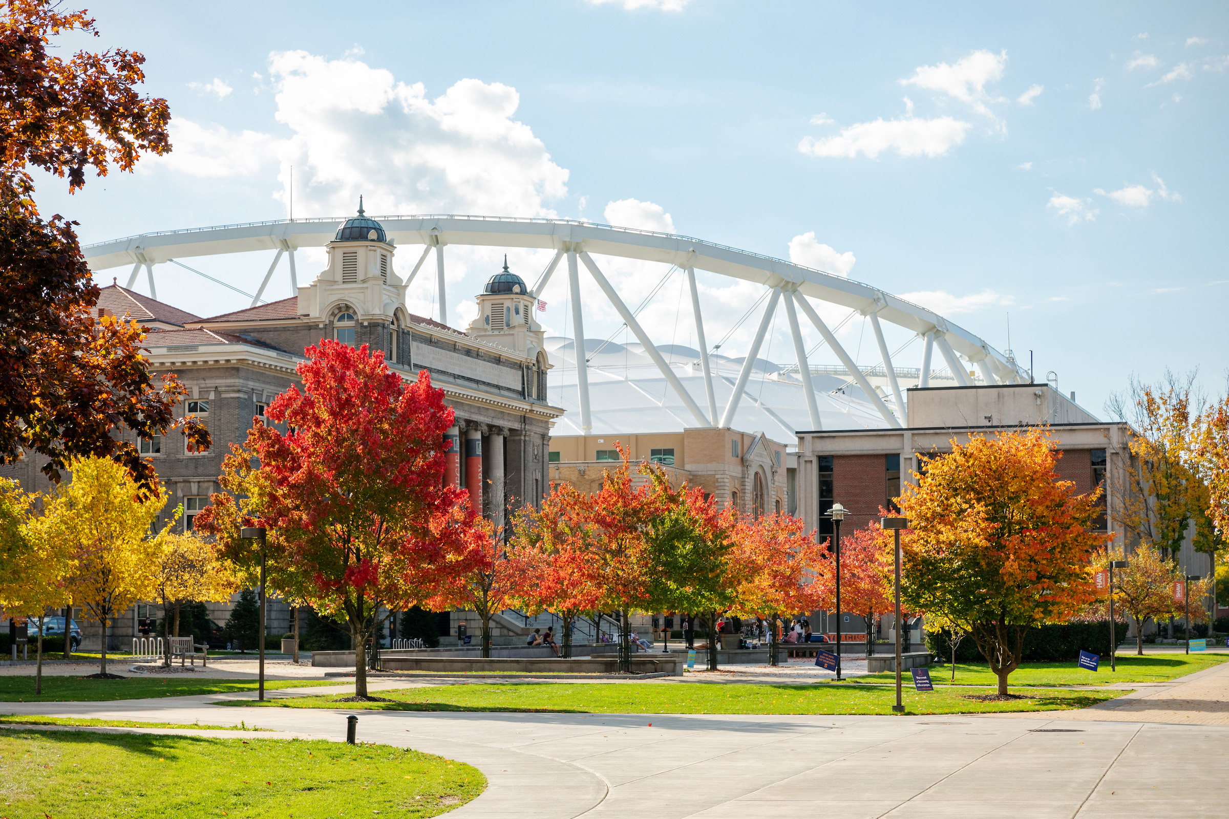 View of the Quad on an autumn day with vibrant red and orange trees in the foreground and a clear blue sky above.
