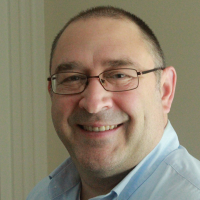 A faculty member smiles while posing for a headshot.