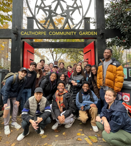 a large group of students stands in front of a community garden's fancy entryway
