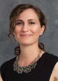 person with black top and necklace looking forward